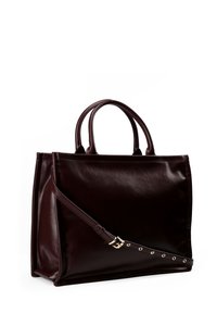Sac fourre-tout en cuir bordeaux avec double anse supérieure, bandoulière amovible, texture lisse et détails en métal doré.