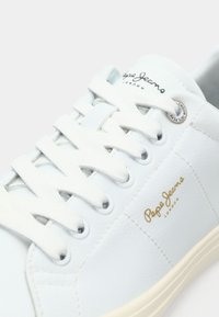 White leather sneaker with round toe, flat laces, and gold "Pepe Jeans London" logo. Features textured upper and light-colored sole.