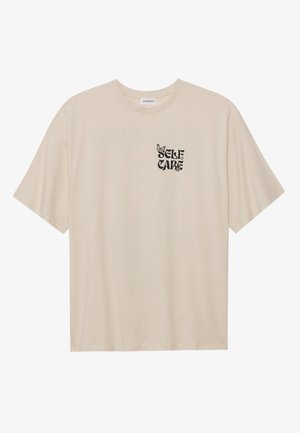 Beige cotton t-shirt featuring short sleeves, a round neckline, and a black graphic print with the phrase "SELF CARE" and a butterfly design.