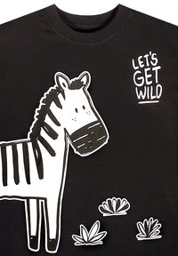 Tegneserie zebra med sort-hvide striber, der står ved siden af tre buske med teksten "LAD OS BLIVE VILDE" på sort baggrund.