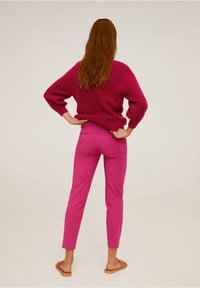 Fuchsia sweater with textured knit, paired with fitted pink trousers, and tan sandals, as viewed from the back.