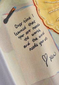 Message manuscrit sur tissu : « Avec le temps, j'ai appris que ton art a besoin du monde, et que le monde a besoin de ton art », avec un croquis de cœur et une signature.