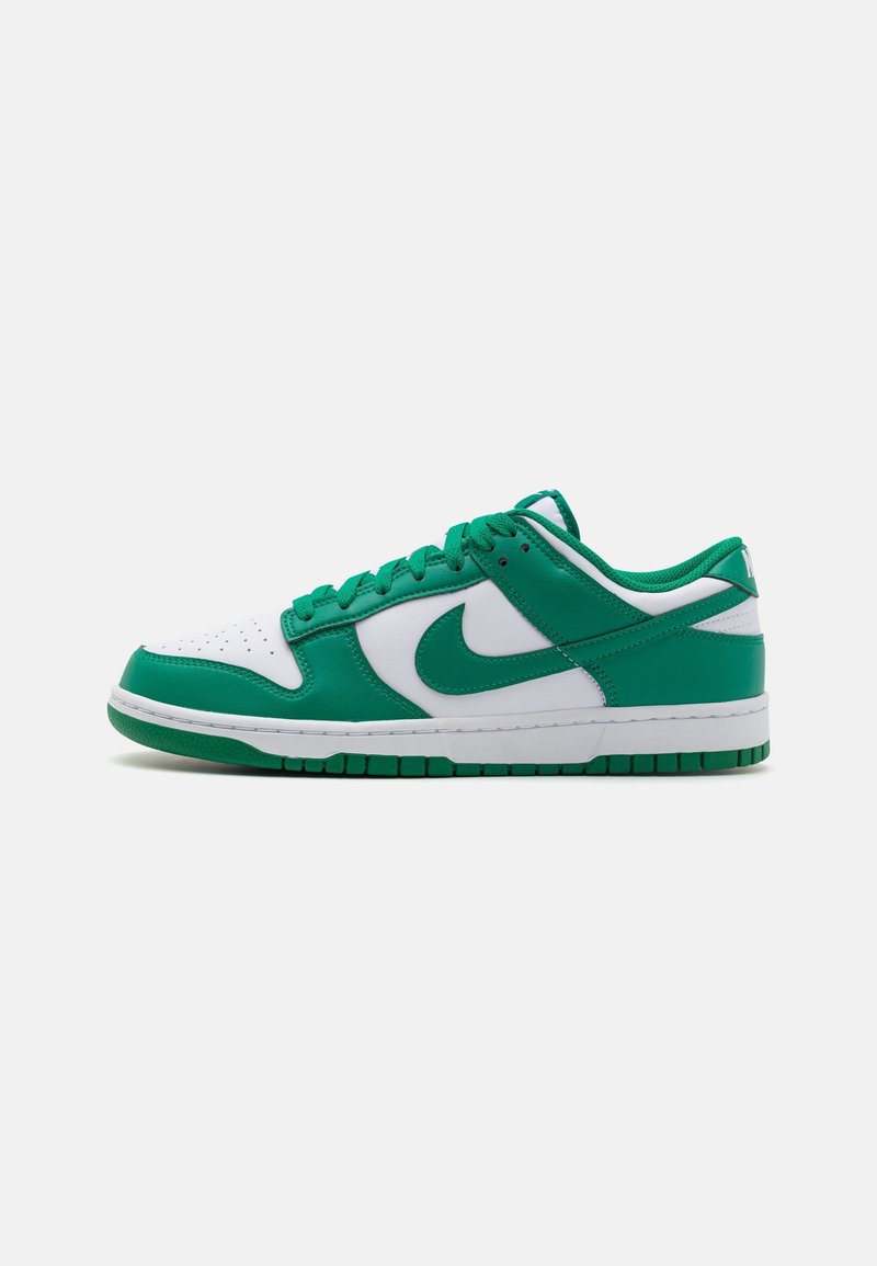 Baskets basses en cuir blanc et vert avec un swoosh Nike vert, des lacets et une semelle verts, vues de côté sur fond blanc.