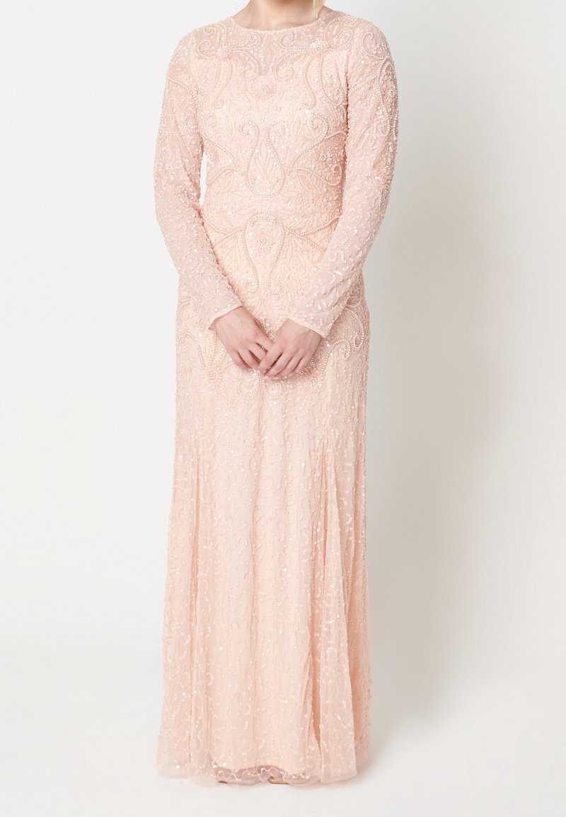 Abito a maniche lunghe e lunghezza fino al pavimento in tessuto color pesca morbido con dettagli intricati di perline e paillettes, caratterizzato da un corpetto aderente e una gonna fluente.