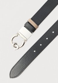 Cintura in pelle nera con finitura strutturata, ferrature in argento e un design unico della fibbia. Presenta una forma sottile e dritta con diverse forature.