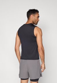 Fekete ujjatlan atletikus felső sima textúrával, szürke rövidnadrággal párosítva, amely finom mintázattal rendelkezik, lazán sportos szabással.