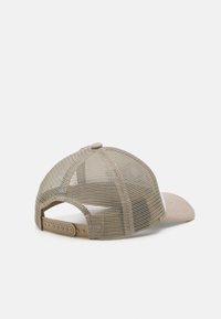 Beige baseball cap with a soft brim, mesh back, and adjustable snap closure. Features stitching details on the brim and logo accent.