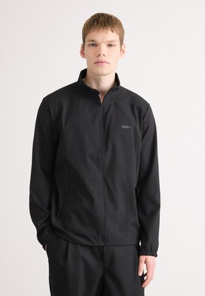 Black zip-up jacket with a stand-up collar, elastic cuffs, side pockets, and a subtle logo on the left chest. Smooth, lightweight fabric.