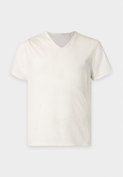 Απλό λευκό κοντομάνικο T-shirt με V-λαιμόκοψη, παρουσιάζεται σε επίπεδη ανοιχτογκρι επιφάνεια.