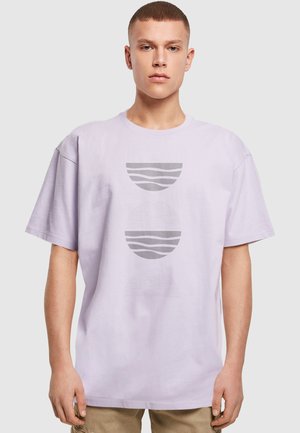 Lys lilla oversized t-shirt lavet af bomuld, med tre cirkulære grafiske designs i grå, med varierede linjemønstre og former.