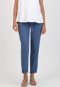 Blue tapered pants featuring a soft texture, roll-up cuffs, and a relaxed fit, paired with a white peplum top and embellished sandals.