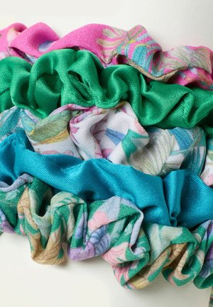 Four fabric scrunchies in pink, green, blue, and multicolored floral patterns, layered and gathered on a white background.