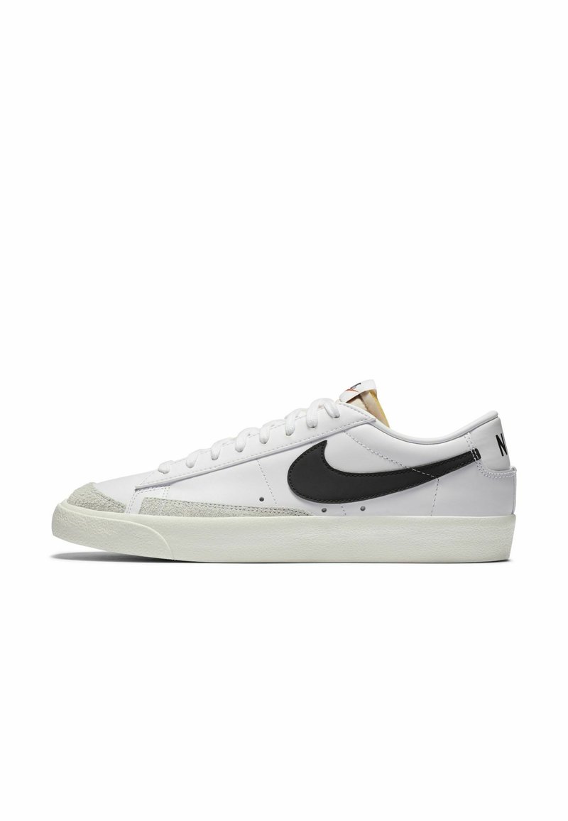 Witte leren sneakers met een zwarte swoosh, een textuur grijze suède neuscap, platte veters en een witte rubberen zool. Opvallende stikdetails.