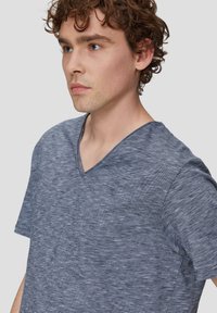 T-shirt z dekoltem w serek w granatowym, melanżowym materiale z teksturowanym, lekko prążkowanym wzorem; krótki rękaw i luźny krój.