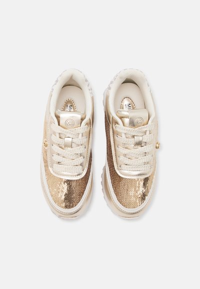 Ζευγάρι μπεζ και χρυσά sneakers με παγιέτες, λευκά κορδόνια και λογότυπο MK στη γλώσσα, φωτογραφημένα από πάνω σε λευκό φόντο.