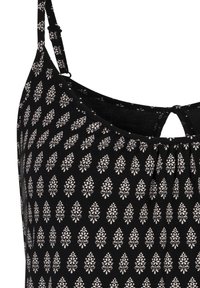 Black fabric tank top with white floral pattern; features adjustable straps and a keyhole detail at the back neckline.