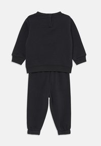Survêtement pour enfants noirs en tissu doux. Comprend un col rond, des poignets côtelés et une taille élastique avec des jambes fuselées.