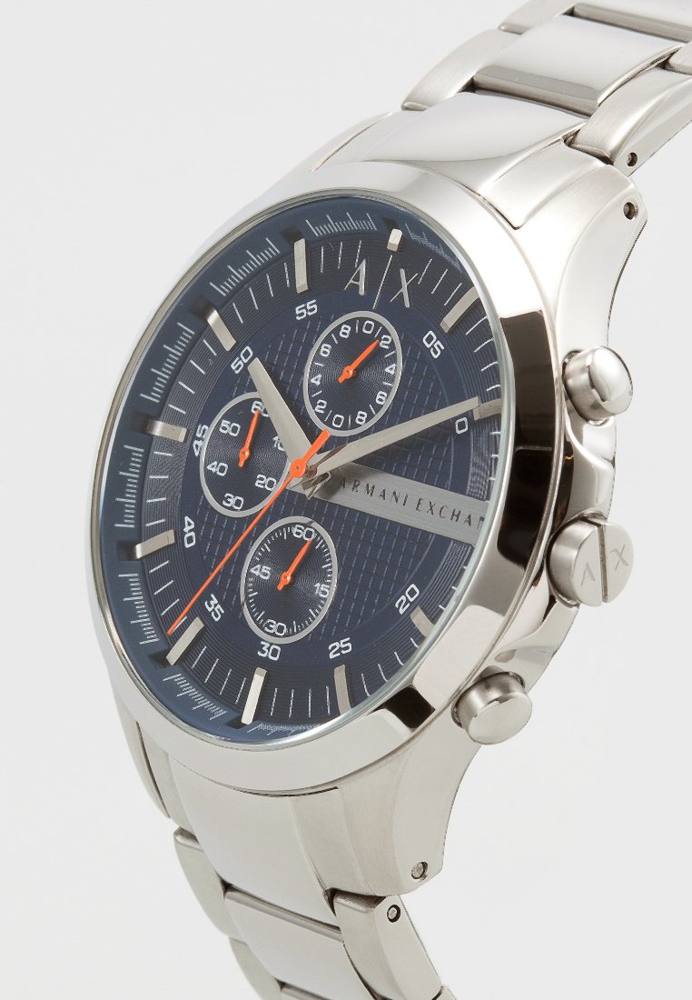 Orologio cronografo in acciaio inossidabile con quadrante blu navy, dettagli argentati, tre piccoli quadranti e particolari arancioni. Bracciale in metallo spazzolato.