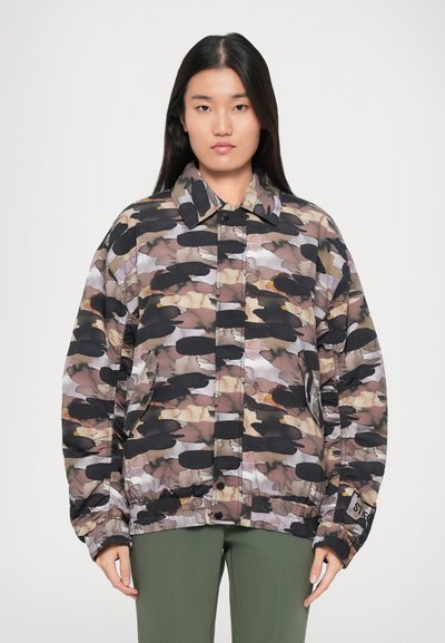 Veste surdimensionnée à motifs camouflage dans des teintes de marron, noir et gris. Dotée d'une fermeture à pression et d'une taille élastique.