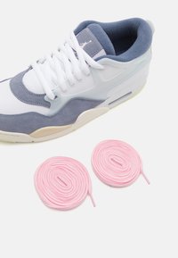 Hvide og grå sneakers med ruskindsdetaljer, mesh-paneler og gummisål; ledsaget af to lyserøde snørebånd, der er snoet på siden.