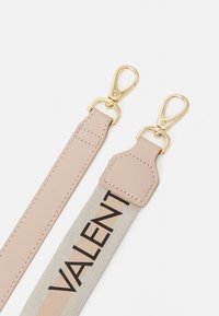 Kožený řemínek se zlatými kovovými sponami, v béžové a krémové barevné kombinaci. Černé logo "VALENT" je tištěno na krémové části.