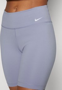 Fioletowe, sportowe szorty z wysokim stanem wykonane z elastycznej tkaniny, o gładkiej fakturze i małym białym logo Nike na pasie.