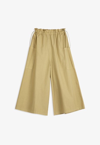 Pantalon beige à jambes larges avec une taille élastique et un cordon de serrage, doté de grandes poches latérales et d'une coupe ample.
