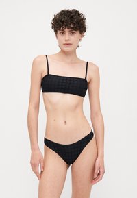 Ensemble de bikini noir avec un haut à bande texturée et un bas à couverture minimale. Caractéristiques des bretelles fines et ajustables ainsi qu'un motif en grille sur le tissu.