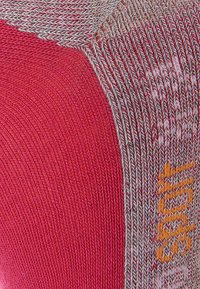 Roter und grauer Strickstoff mit einem strukturierten Muster, das ein markantes orangefarbenes Akzentdetail aufweist, glatte Oberfläche und unterschiedliche Fadendicken.