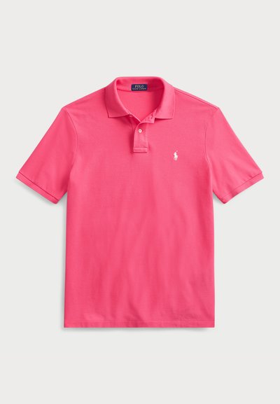 Polo en coton rose vif, doté d'une patte de boutonnage à trois boutons, de manches courtes et d'un petit logo blanc brodé sur la poitrine.