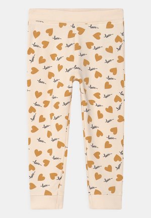 Kremowe legginsy dziecięce z brązowymi serduszkami i słowem „love” powtarzającym się w czarnym kursywie.