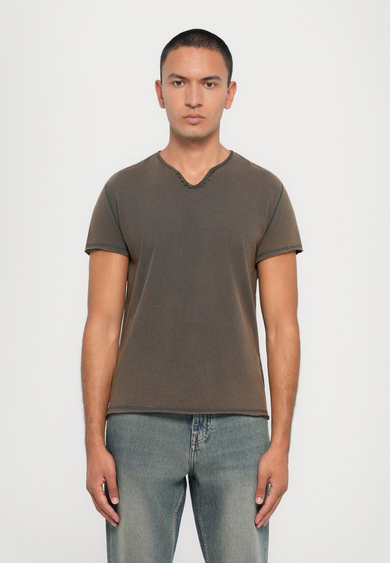 Brown short-sleeve t-shirt with a V-neck and small buttons. Soft fabric, fitted shape, and contrasting stitching at the hem and sleeves.