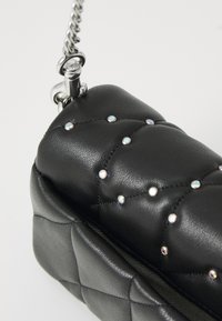 Black quilted faux leather bag with silver chain handle. Features crystal accents across the surface. Compact rectangular shape.