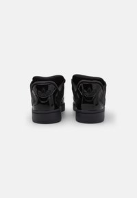 Svarta lacklädersneakers med en slät yta. Förstärkt häl, vadderad krage och präglad logodetalj på baksidan. Low-top design.