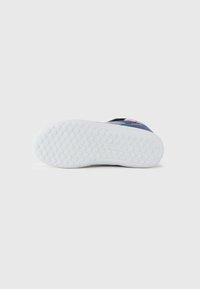 Blauwe sneakers met een witte rubberen zool die is voorzien van een tekstuurlijk grippatroon. Accenten zijn onder andere een rode logolabel nabij de hak.