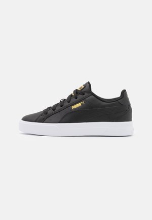 Czarny niski sneaker Puma ze złotymi logo i grubą białą podeszwą, widziany od zewnętrznej strony na jednolitym jasnym tle.