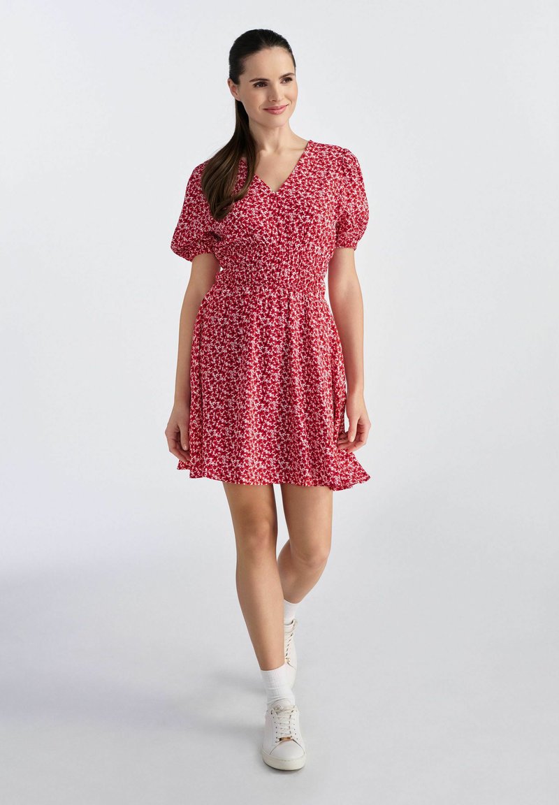 Czerwona sukienka w kwiaty z krótkimi bufkami i dopasowaną górą, z rozkloszowanym dołem. Wykonana z lekkiego materiału z delikatnym wzorem.
