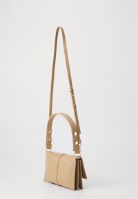 Beżowa skórzana torebka o prostokątnym kształcie, z płaskim przodem, krótkim uchwytem na górze oraz długim, regulowanym paskiem. Posiada złote metalowe detale.