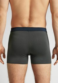 Pánské boxerky ve tmavě šedé tkanině s měkkým elastickým námořnickým páskem. Design je přiléhavý s hladkou texturou.