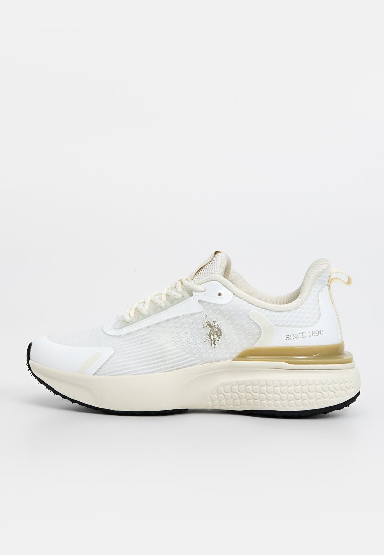 Zapatilla deportiva blanca con parte superior de malla texturizada, acento dorado en el talón, suela ligera y logo prominente en el costado. Suela de goma para tracción.