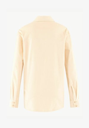 Lys beige corduroy skjorte med krave, lange ærmer og knaplukninger ved manchetterne. Har lodret ribbet tekstur.