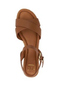 Brown flat sandal with crossed straps, ankle strap with gold buckle, cushioned sole, and "Dune London" logo on footbed.