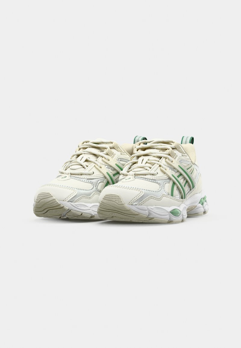 Baskets blanches avec des accents verts, présentant un dessus en mesh et en matière synthétique, une semelle texturée et un système de laçage proéminent. Conception à bout arrondi.