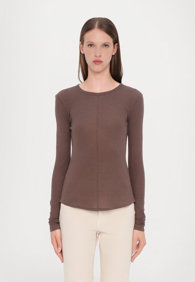 Maglietta marrone a maniche lunghe in tessuto morbido, con scollatura rotonda, forma aderente e dettagli delle cuciture piatte, abbinata a pantaloni beige.