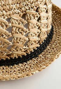 Sombrero de paja tejido en tonos naturales, con una banda trenzada negra, forma circular y un diseño de tejido abierto para ventilación.