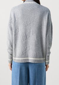 Hellgrauer Strickpullover mit strukturiertem Logo-Muster, hohem Kragen und geripptem Saum mit einem kontrastierenden weißen Streifen.