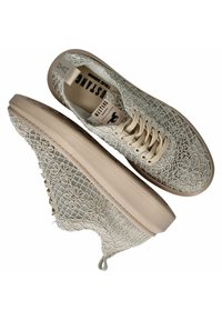 Sneakers con allacciatura realizzati in un alto tessuto beige chiaro, caratterizzati da ricami floreali. La suola in gomma è spessa e testurizzata, aumentando la durata.