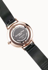 Montre ronde avec un dos en acier inoxydable rose gold et un bracelet texturé noir ; dispose d'un mouvement japonais et d'une résistance à l'eau.