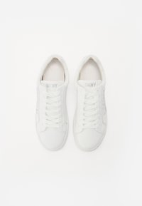 White sneakers made of smooth leather with flat laces, rubber soles, and subtle branding on the tongue and side in light gray.