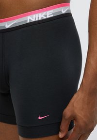 Μαύρα ανδρικά εσώρουχα Nike boxer με ροζ και γκρι ζώνη μέσης. Διαθέτουν μικρό ροζ λογότυπο στην κάτω αριστερή πλευρά και υλικό απαλό, ελαστικό.
